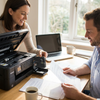 A couple in a sunlit home office, with the woman inserting a Balloon Brand LC3013XL Black ink cartridge into a Brother printer while the man reviews printed documents.