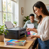 A woman in a bright home office is about to install the Balloon Brand Brother-LC401XL-Magenta ink cartridge into a printer, with a man smiling in the background.