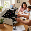 A person installs a Balloon Brand LC404 Black ink cartridge into a printer in a home office, with a family working in the background.